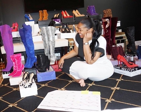 A picture of Rashidah Ali sitting along with the shoes at her shop.